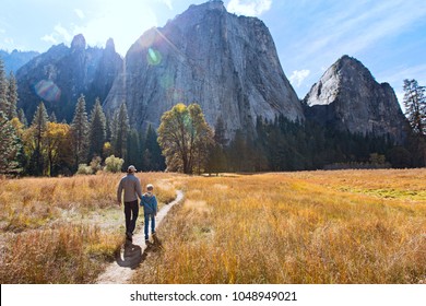 back view of active family of two, father and son, enjoying valley and mountain view in yosemite national park, california, active family vacation concept