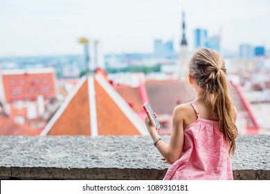 Back View Of Adorable Girl Outdoors Exploring Tallinn Old Town On Summer Day