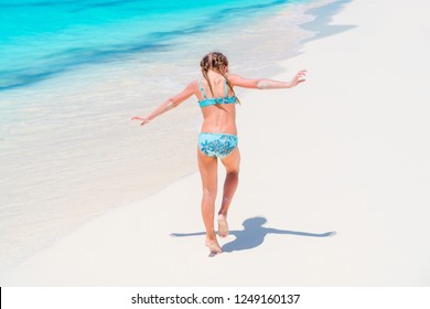 Back view of adorable little girl having fun on beach tropics vacation