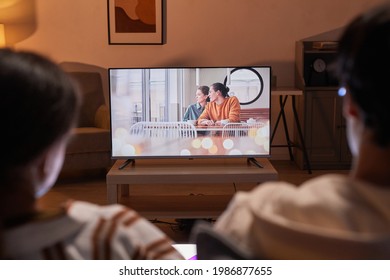 Back view of adult couple watching movies at home while sitting on sofa, focus on TV screen - Powered by Shutterstock