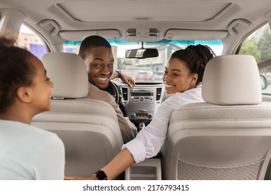 Back View Of African American Family Sitting In New Car Smiling To Each Other Enjoying Summer Road Trip Together. Automobile Rent And Purchase Concept. Selective Focus