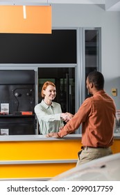 Back View Of African American Man Shaking Hands With Happy Car Dealer