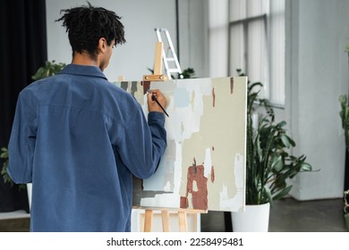 Back view of african american man painting on canvas in studio - Powered by Shutterstock