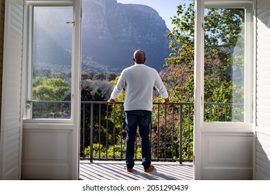 Back view of african american senior man standing on balcony and looking into distance. retirement lifestyle, spending time at home and garden. - Powered by Shutterstock