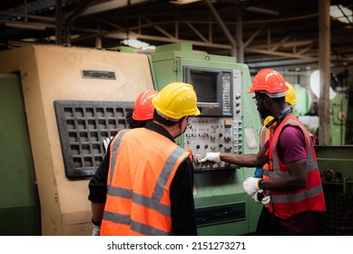 Back View Of An African-American Male Foreman Are On The Job Training Or Coaching In Safety Use Of Lathes In The Workplace For Male And Female Workers In Heavy Industrial Manufacturer Factory.