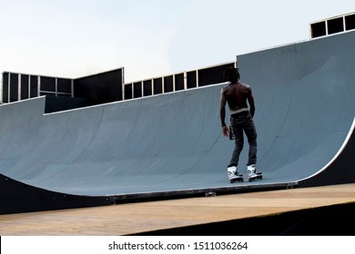 Back view of Afro American inline roller skater rolling off the ramp