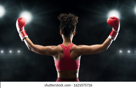 Back view of afro woman boxer champion celebrating win over stadium background, panorama