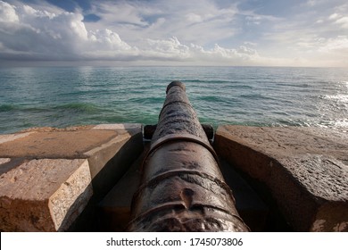 Back view from ancient cannon heading to the sea against the backdrop of a dramatic sky. These type of cannon were used in order to protect them from invaders. Concept of protection and power. Cannon 