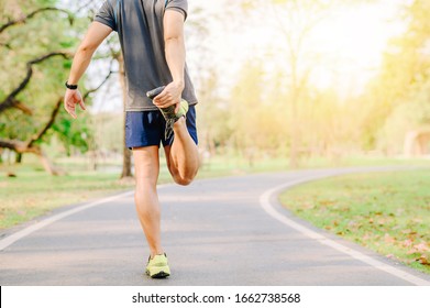 Back View Of Asia Man Runner Doing Stretching Exercise, Warm Up Before For Running In Morning On Track In The Park 