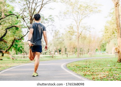 Back View Of Asia Man Runner Doing Stretching Exercise, Warm Up Before For Running In Morning On Track In The Park 