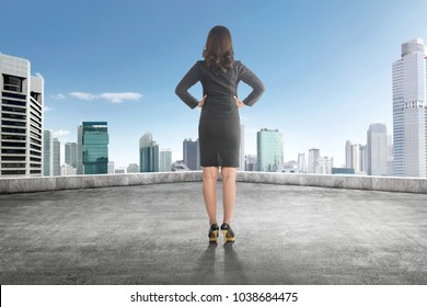 Back View Of Asian Business Woman With Hand On Her Waist On The Rooftop Looking At Blue Sky