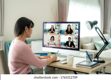 Back view of Asian business woman talking to her colleagues about plan in video conference. Multiethnic business team using computer for a online meeting in video call.