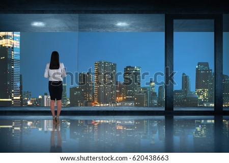 Back view of asian business woman standing looking at the city through window