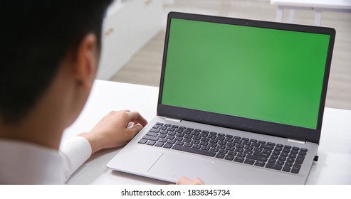 Back View Of Asian Businessman Look At Green Screen Laptop In Office