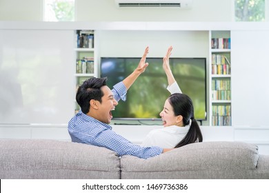 Back View Of An Asian Couple Happy Watching Tv Together