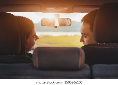 Back View Of Asian Couple Looking Each Other In Hatchback Car At Camping Picnic Place With Green Meadow And Mountain. People Lifestyles And Transportation Concept. Valentines Day And Honeymoon Wedding