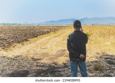 Back View Of Asian Elderly Man Farmer Use Phone For Business To Plan Farming In Wilderness. Male Farmers Consult With Landowners To Cultivate Crops In Soil Field. Farm And Agricultural Business.