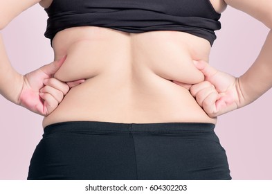 Back View. Asian Fat Women Has Overweight. She Used Hands Squeezing Excess Fat Of The Waist. Isolated On Violet Background. She Wants Lose Weight. Concept Of Surgery And Subcutaneous Fat Breakdown.