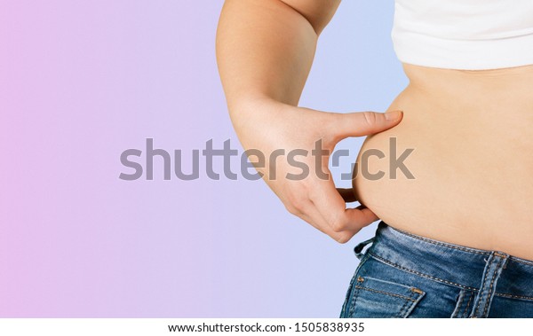 back\
view. asian fat women has overweight. she shows excess fat of the\
waist. isolated on violet background. she wants lose weight.\
concept of surgery and subcutaneous fat\
breakdown.