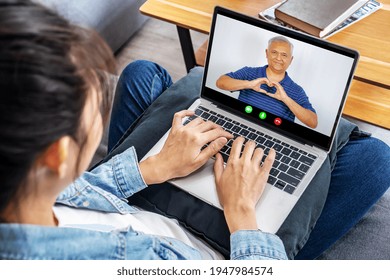 Back View Of Asian Girl Rest At Home Talk On Video Call On Laptop With Happy Senior Father, Young Woman Relax On Couch Speak Chat Online With Smiling Mature Dad, Use Webcam On Computer

