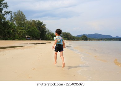 Back view of Asian little boy having fun running on tropical sand beach - Shutterstock ID 2254035093