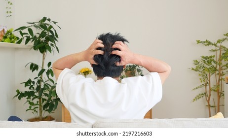 Back View Of Asian Man Holding Her Head On The Sofa