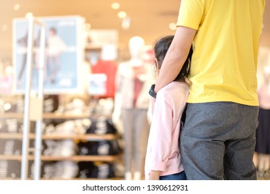 Back view Asian man on yellow t-shirt and his daughter standing in front of clothing store in Modern Shopping mall waiting his wife shopping in store. - Shutterstock ID 1390612931