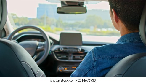 Back View Of Asian Man Riding An Autonomous Self Driving Car With No One In Driver Seat On The Road