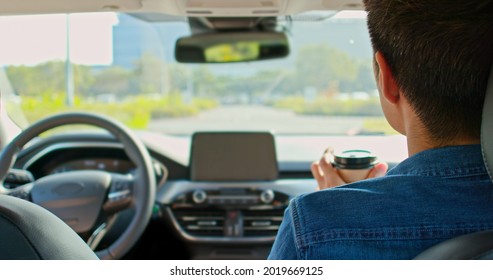 Back View Of Asian Man Riding An Autonomous Self Driving Car With No One In Driver Seat And Drink Coffee On The Road