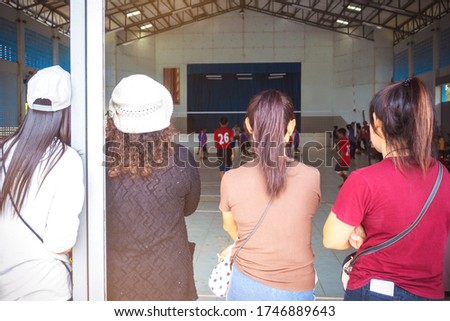 Back view of asian parents cheering childrens learn to playing volleyball in school. Physical education
