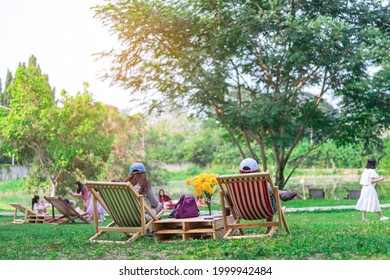 Back view of Asian senior lover sit to relax on garden chair and by the table in garden. Summer vacation in green surroundings. Happy person outdoors relaxing on deck chair in garden. Outdoor leisure. - Powered by Shutterstock