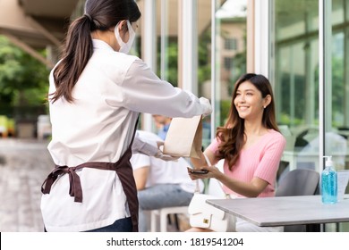 Back view of asian waitress with face mask give order of take out food bag to attractive woman female customer. Take away or take-out food service concept in new normal after coronavirus pandemic. - Powered by Shutterstock