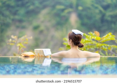 back view of asian woman sitting in hot spring pool relaxing - Shutterstock ID 2196515707