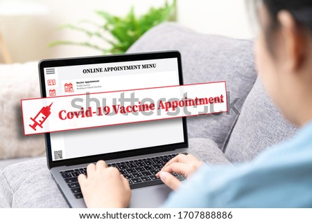 Back view of asian woman using online health appointment, booking or reserve coronavirus or covid-19 vaccine in concept social distance healthcare in quanrantine people at home using laptop computer.