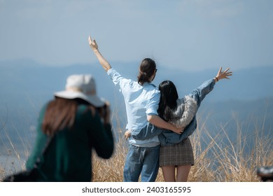 Back view of asian women traveler standing on top of mountain and enjoy nature view and there was a photographer taking photos.