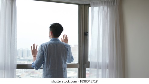 Back View Of Asian Young Man Wearing Face Mask Stay Isolation At Home For Self Quarantine Due To Epidemic Of COVID19 - He Looks Out The Window