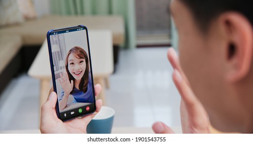 Back View Of Asian Young Man Has Video Chat With Girlfriend By Smart Phone In The Living Room At Home