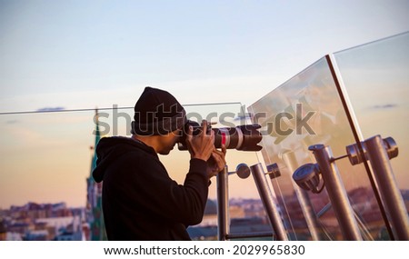 Back view of  Asian young man photographer using a camera takeing a picture of view in red square skyline  with sunset sky scene background in the, Moscow,Russia