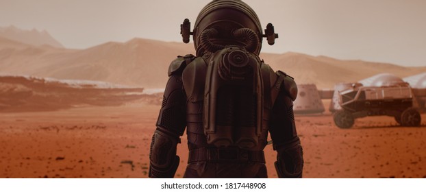 Back view of astronaut wearing space suit walking on a surface of a red planet. Martian base and rover in the background. Mars colonization concept - Shutterstock ID 1817448908