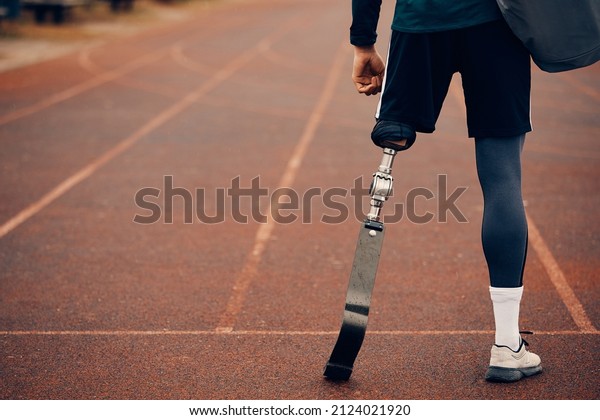 Back view of athlete with a\
prosthetic leg on running track at the stadium. Copy\
space.