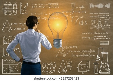 Back view of attractive thoughtful young european businessman with glowing light bulb on chalkboard wall background with mathematical formulas. Science, idea and education background - Powered by Shutterstock