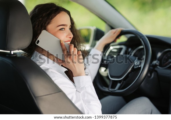 Back\
view of an attractive young business woman looking over her\
shoulder and talking the phone while driving a\
car.