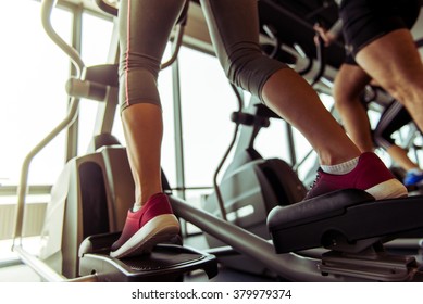 Back view of attractive young people working out on an elliptical trainer in gym - Powered by Shutterstock