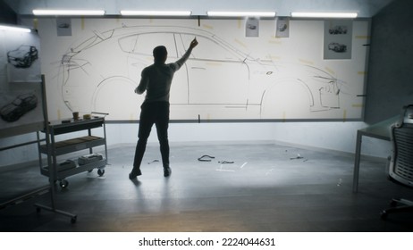 Back View Of Automotive African American Male Designer Drawing Sketch Blueprint With Marker, Developing Futuristic Electric Car Design On Whiteboard. Work In Modern Car Design Development Studio.