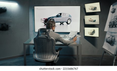 Back View Of An Automotive Graphic Designer Draws Sketch Of The Prototype Model Of A Car Using Stylus Pen In A High Tech Innovative Laboratory. Automotive Industry. Modern Studio With LED.