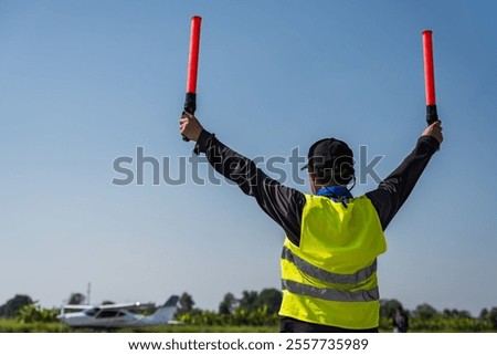 Back view aviation traffic controller man signaling for small plane landing