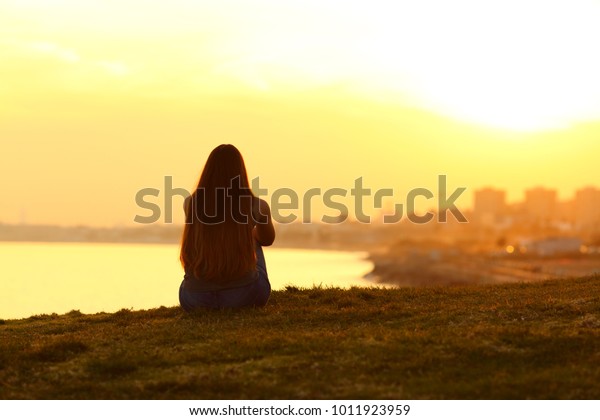 背景に暖かい光で街の夕日を見ている一人の女性の背景にバックライト の写真素材 今すぐ編集