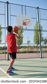 Back View Of A Basketball Kid Player Throwing The Ball To The Basket. Shooting Basketball.