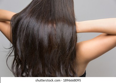 Back view of beautiful brown haired woman on gray background.