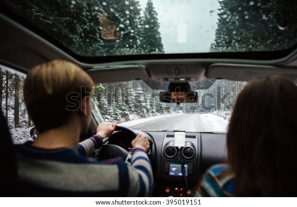Back view of beautiful couple driving in car\
through winter forest